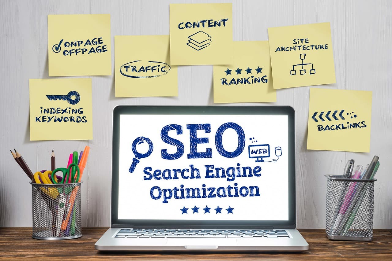 Un ordinateur portable affichant le mot SEO, entouré de notes manuscrites listant les leviers du référencement